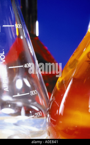 Close up di palloni di chimica con l'arancione e il rosso contenuto contro sfondo blu Foto Stock