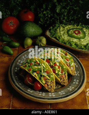 Tacos di manzo messicano w Guacamole in piastrelle rustiche impostazione con verdure fresche in background. Foto Stock