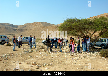 Israele pianure del nord del deserto del Negev un gruppo di viaggiatori essendo informato sotto un ombrello Thorn Foto Stock