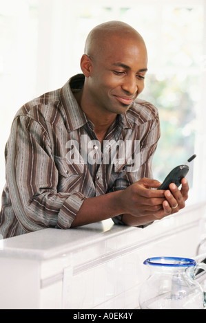 Uomo sorridente con il telefono cellulare a casa Foto Stock