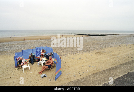 Una famiglia di ricoveri dal vento sulla spiaggia a Cromer REGNO UNITO Foto Stock