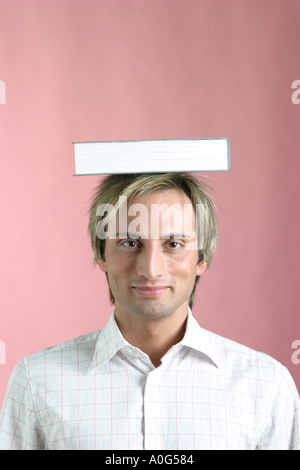 Giovane con un libro bilanciato sulla sua testa Foto Stock