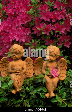 Romance: argilla rossa in ceramica angel figurine seduto su un muro di mattoni circondata da edera e fioritura azalee, Georgia USA Foto Stock