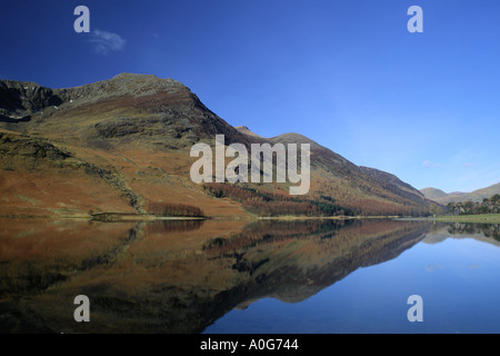 Alto stile si riflette nelle calme acque del Buttermere contro un cielo blu Parco Nazionale del Distretto dei Laghi Foto Stock