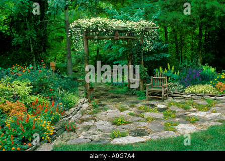 Rustico ramoscello di cedro arbor con vite in fiore da lastricato patio nel giardino fiorito Missouri USA Foto Stock