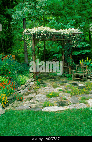 Rustico ramoscello di cedro arbor con vite in fiore da lastricato patio nel giardino fiorito Missouri USA Foto Stock