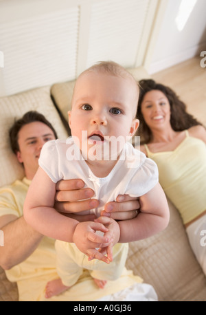 Infant tenuto dalla coppia sorridente Foto Stock