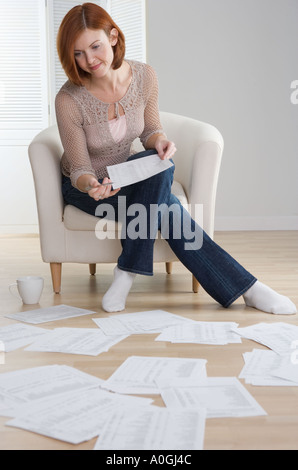 Redheaded donna carte di smistamento sul pavimento Foto Stock