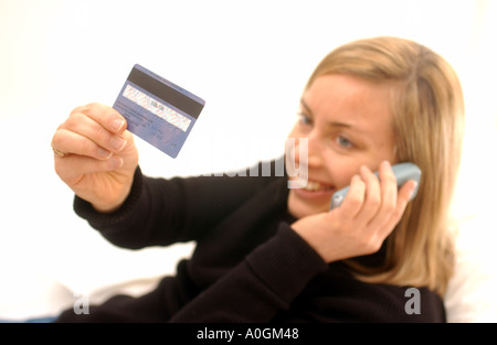 Donna utilizzando la carta di credito per telefono Foto Stock