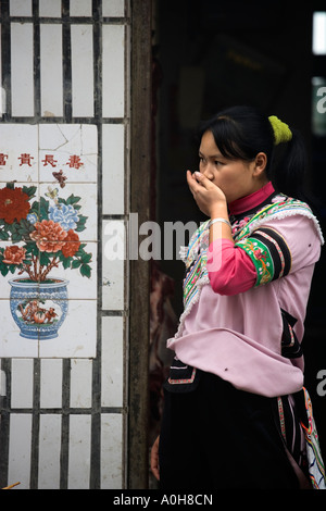 Yi donna di minoranza nella porta con la mano sulla bocca, Shengcun, Yuanyang, Yunnan, Cina Foto Stock