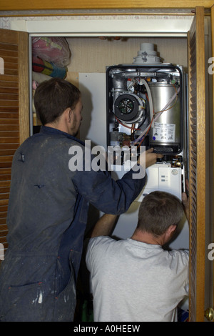 Due adulti i lavoratori di sesso maschile di installare un nuovo Combi caldaia in una casa. Foto Stock