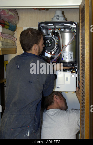 Due adulti i lavoratori di sesso maschile di installare un nuovo Combi caldaia in una casa. Foto Stock