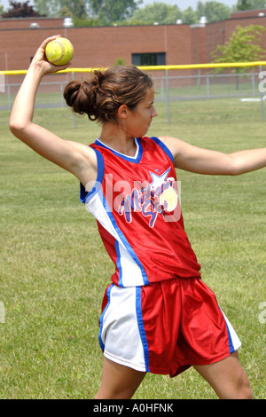 Ragazza adolescente giocando in una major league Softball lancia la palla Foto Stock