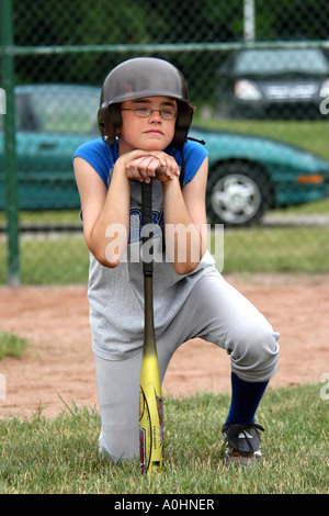 Ritratto di un ragazzo adolescente di prendere parte ad un softball practie sessione in Michigan che poggia il mento su una mazza da baseball Foto Stock