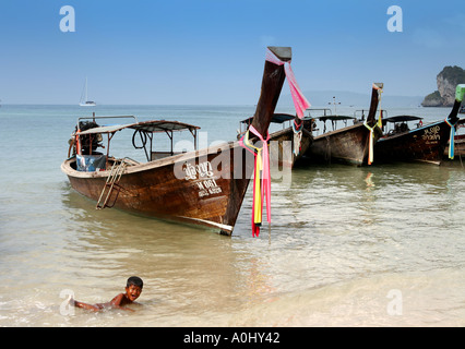 THA Thailandia Krabi Railay Beach long tail barche ragazzo giocando in acqua Foto Stock