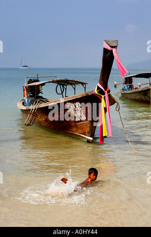 THA Thailandia Krabi Railay Beach long tail barche ragazzo giocando in acqua Foto Stock