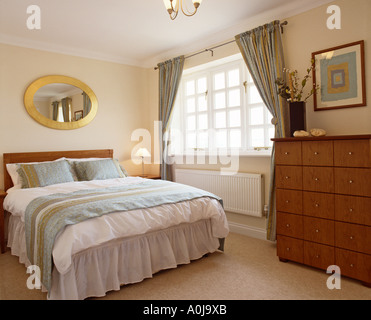 Una tradizionale camera da letto con letto doppio, ovale specchio dorato,  guardaroba Foto stock - Alamy