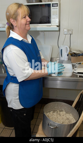 Donna preparare torte pesce in pescheria shop Foto Stock