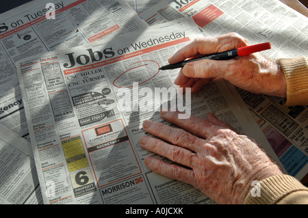 Le mani di un uomo anziano tenendo una penna che sta utilizzando a cerchio lavori in annunci Foto Stock