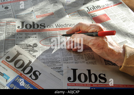 La mano di un uomo anziano tenendo una penna che sta utilizzando a cerchio lavori in annunci Foto Stock