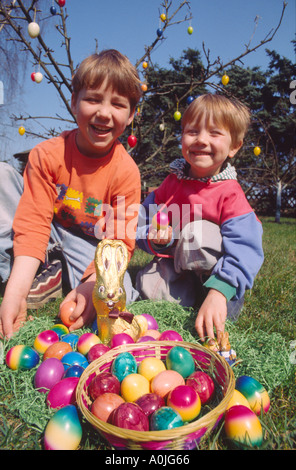 I bambini a giocare all'aperto nel giardino con dipinto di uova di Pasqua in un cestello Foto Stock