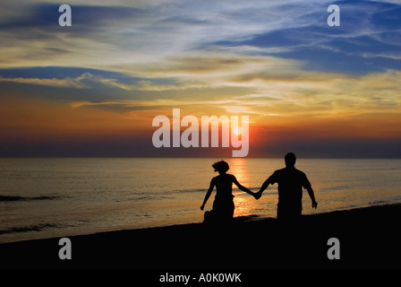 Coppia romantica camminare tenendo le mani al tramonto Foto Stock