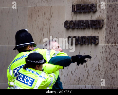 Due ufficiali della polizia in lotta con un uomo al di fuori di Leeds Pretura, Yorkshire Foto Stock