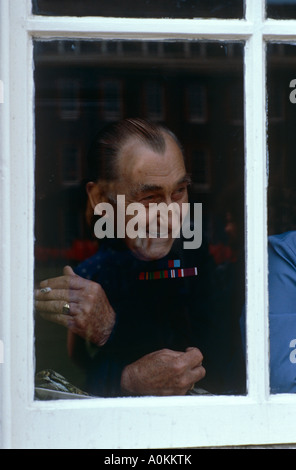 Un pensionato di Chelsea orologi fondatori parata del giorno da una finestra al Royal Hospital Chelsea, London, Regno Unito Foto Stock