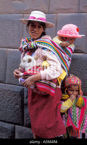 Donna indigena in abiti tradizionali con due bambini e un agnello nelle sue braccia a Cusco in Perù Foto Stock