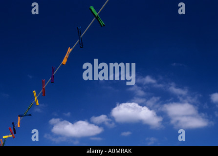 Stendiabiti multicolore appesi su una linea di stendibiancheria con nuvole bianche e cielo blu Foto Stock