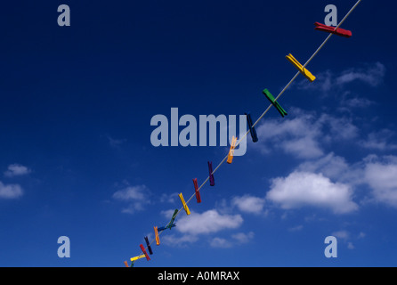 Stendiabiti multicolore appesi su una linea di stendibiancheria con nuvole bianche e cielo blu Foto Stock