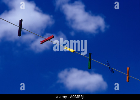 Stendiabiti multicolore appesi su una linea di stendibiancheria con nuvole bianche e cielo blu Foto Stock