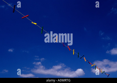 Stendiabiti multicolore appesi su una linea di stendibiancheria con nuvole bianche e cielo blu Foto Stock