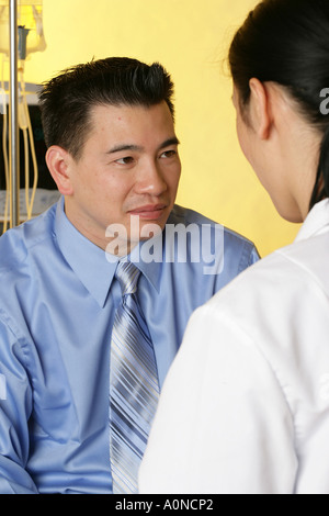 Asian medico donna si consulta con paziente di sesso maschile durante la visita medica. Foto Stock