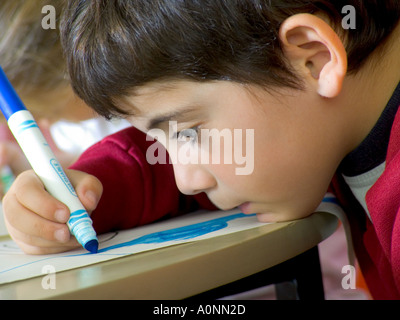 Vicino sul neonato Ragazzo con libro da colorare e pastelli nella scuola materna di classe d'arte Foto Stock