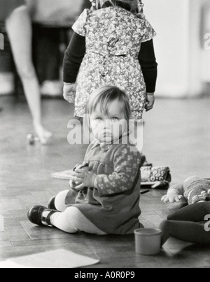 Bambina bambino interni a giocare a scuola seduti sul pavimento in parquet lucidato. Foto Stock