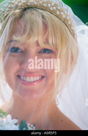 Outdoor ritratto di felice giovane donna sposa indossa velo nuziale. Foto Stock