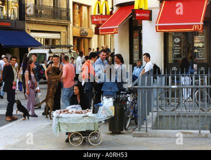 Il commercio equo e solidale uomo vendere peanut sul bambino passeggino da Mc Donald s occupato animata strada trasversale donna cane Montpellier Francia Europa Foto Stock