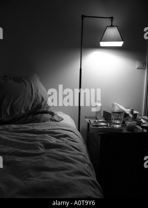 Comodino illuminante vetro bicchieri di acqua lozione e di altri dati personali voci al posto letto Foto Stock