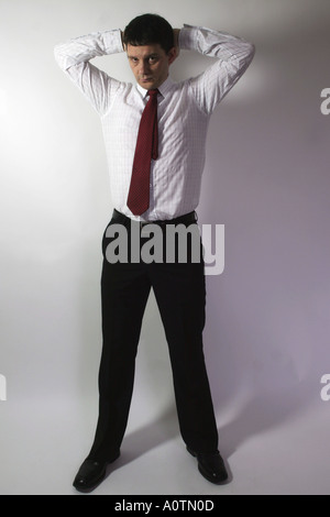 Busines uomo con le braccia aperte dietro la testa sembra assertively presso la fotocamera Foto Stock