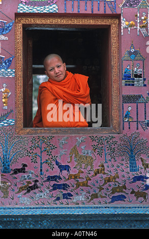 Monaco novizio nella finestra del mosaico decorato tempio di Wat Xieng Thong Luang Prabang s più famoso monastero Laos sito UNESCO Foto Stock