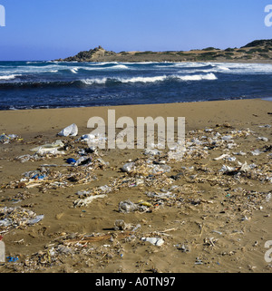 Guardando attraverso una spiaggia sulla costa nord con sabbie inquinate coperti in politene e rifiuti di plastica spazzatura Girne Cipro del Nord Foto Stock