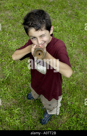 Ragazzo giovane prendendo obiettivo durante la riproduzione con un bambù pistola ad acqua. Foto Stock