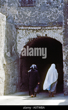 AFRICA MAROCCO Tangeri le donne musulmane in velo tradizionale a piedi attraverso antichi archway in la casbah di Tangeri Foto Stock