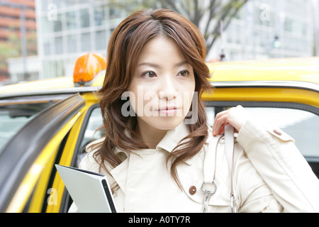 Chiudere fino a una giovane donna in piedi vicino a un taxi e in possesso di un file Foto Stock
