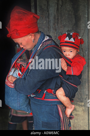 Madre con bambino indossato in un panno riporto Red Dzao minoranza hilltribe Sapa regione del Nord Vietnam Foto Stock