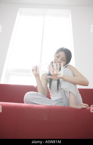 Basso angolo vista di una giovane donna il deposito di lei le unghie e a parlare su un telefono mobile Foto Stock