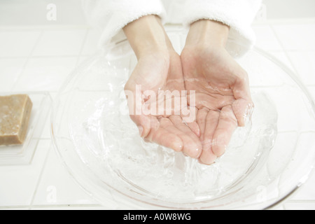 Angolo di alta vista di mani umane su una tazza di acqua Foto Stock