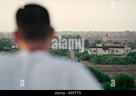Dherinia, Cipro del Sud. Un giovane greco-cipriota sguardi maschio attraverso la linea verde in direzione controllata turca di Famagosta. Foto Stock