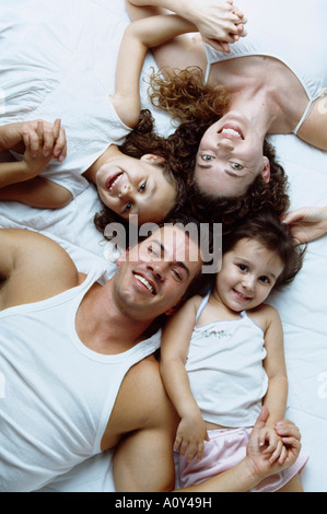 Ritratto di genitori giacente con le loro due figlie sul letto Foto Stock